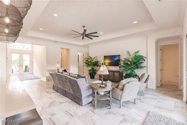 living room with ceiling fan, french doors, ornamental molding, and a tray ceiling