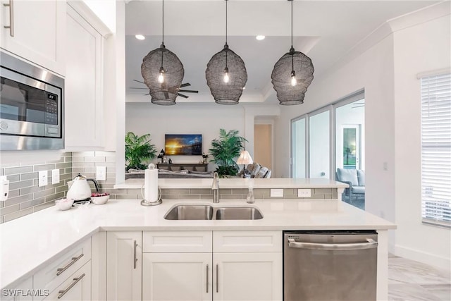 kitchen featuring appliances with stainless steel finishes, backsplash, sink, white cabinets, and hanging light fixtures