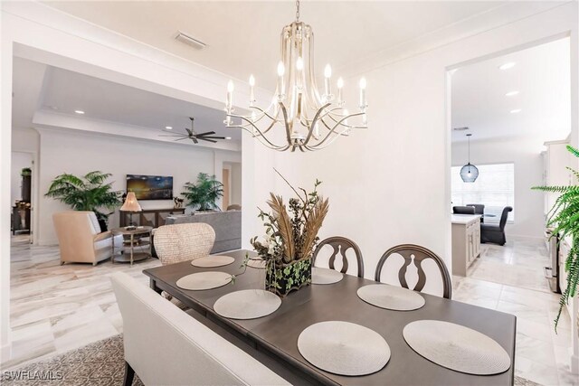 dining room featuring ceiling fan with notable chandelier, a raised ceiling, and crown molding