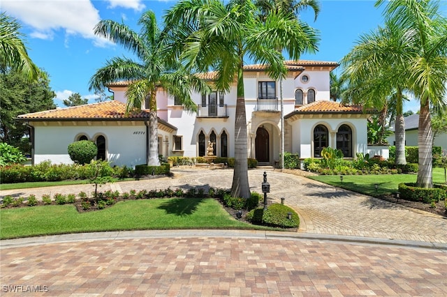 mediterranean / spanish-style home with a front yard, a balcony, and french doors