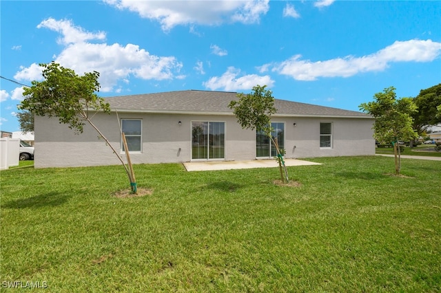 back of house with a lawn, a patio area, and stucco siding