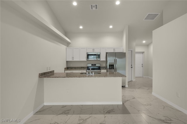 kitchen featuring dark stone counters, white cabinetry, stainless steel appliances, kitchen peninsula, and sink