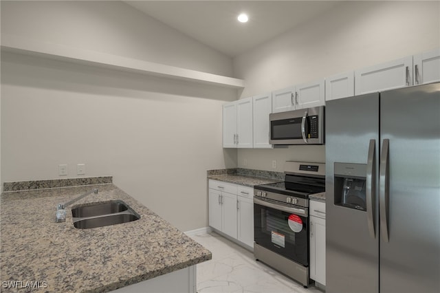 kitchen with white cabinetry, stainless steel appliances, sink, light stone countertops, and vaulted ceiling