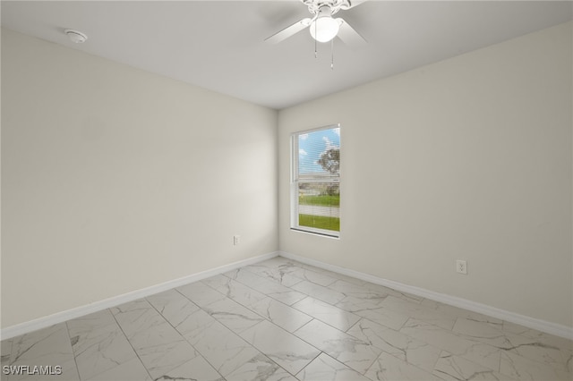 spare room with marble finish floor, baseboards, and a ceiling fan