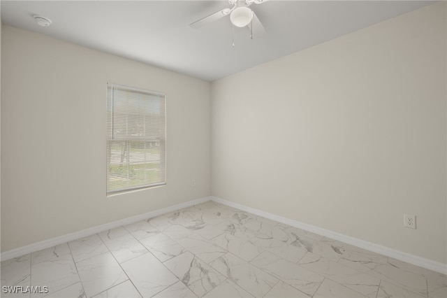 unfurnished room featuring marble finish floor, a ceiling fan, and baseboards