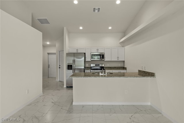 kitchen with dark stone counters, white cabinetry, stainless steel appliances, kitchen peninsula, and sink