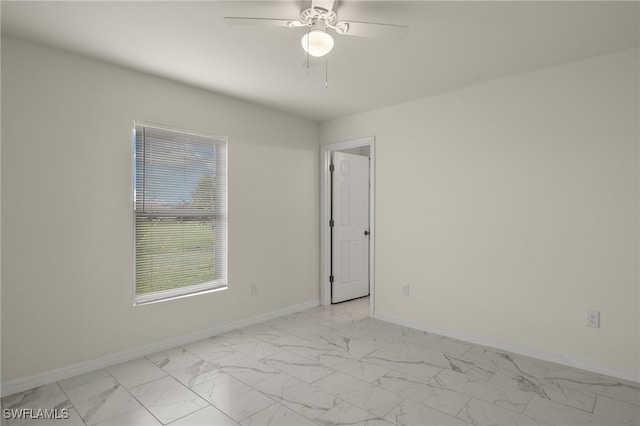 unfurnished room with marble finish floor, ceiling fan, and baseboards