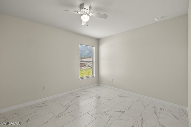 unfurnished room with marble finish floor, ceiling fan, and baseboards