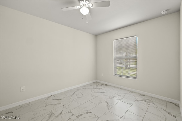 empty room featuring marble finish floor, ceiling fan, and baseboards