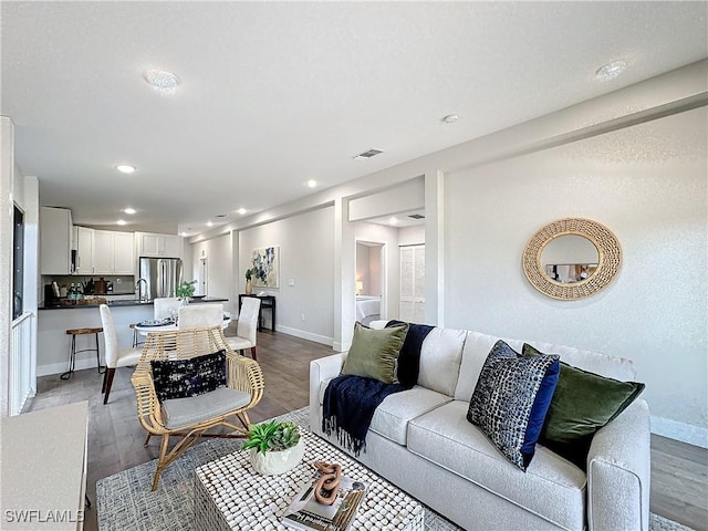 living area featuring recessed lighting, visible vents, baseboards, and wood finished floors