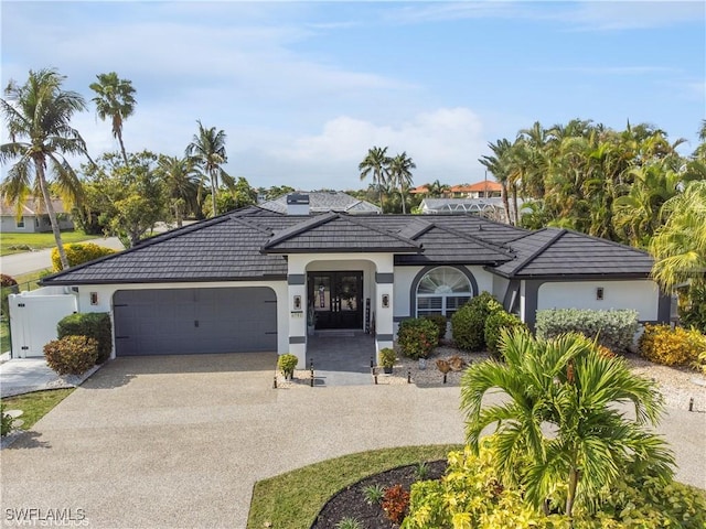 view of front of house with stucco siding, driveway, an attached garage, and fence