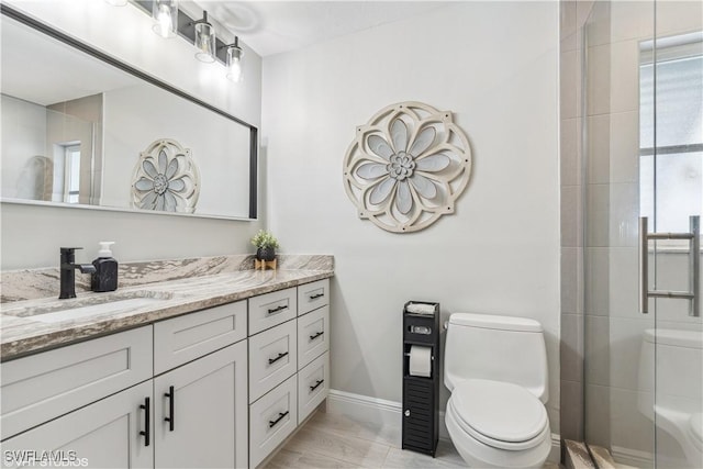 full bathroom featuring a shower stall, baseboards, vanity, and toilet