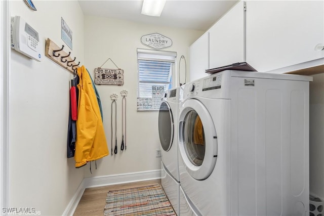 clothes washing area with washer and clothes dryer, wood finished floors, cabinet space, and baseboards