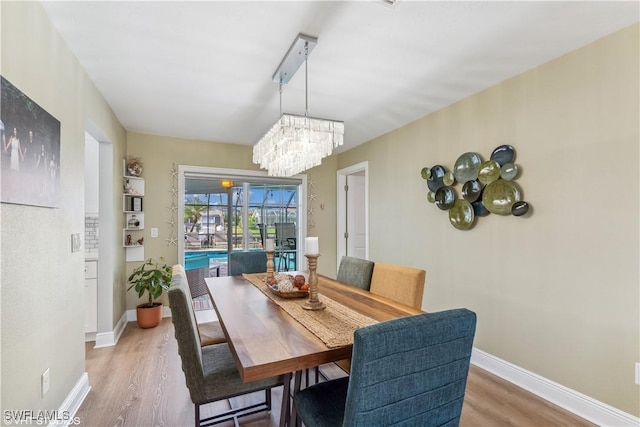 dining area featuring an inviting chandelier, baseboards, and wood finished floors