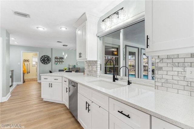 kitchen with visible vents, decorative backsplash, dishwasher, white cabinets, and a sink