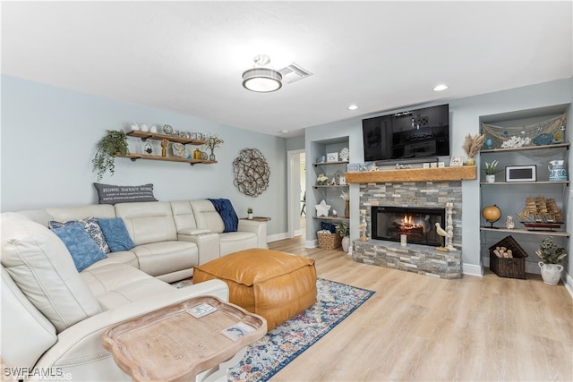 living room featuring wood-type flooring, built in shelves, and a fireplace