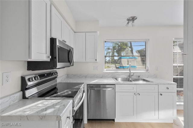 kitchen featuring appliances with stainless steel finishes, light hardwood / wood-style floors, sink, light stone counters, and white cabinets