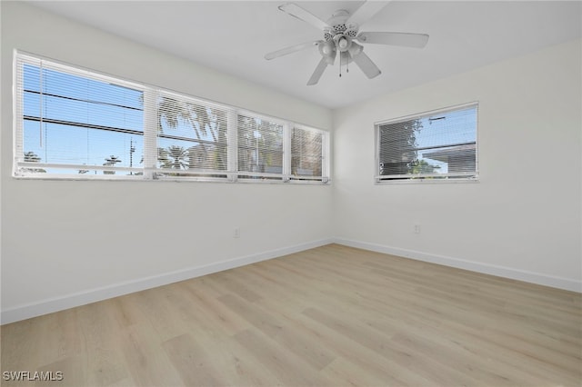 empty room with a wealth of natural light, ceiling fan, and light hardwood / wood-style floors