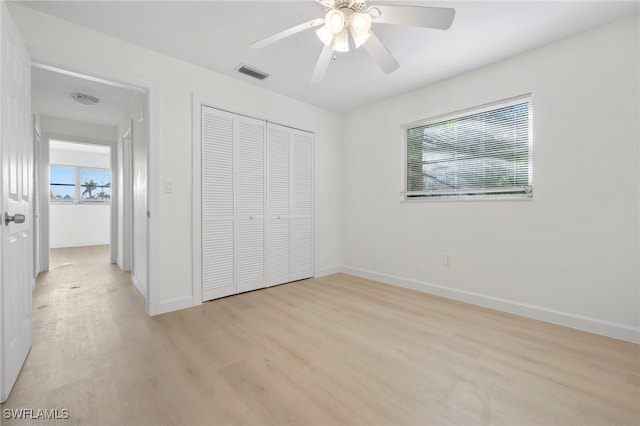 unfurnished bedroom featuring light wood-type flooring, multiple windows, and a closet