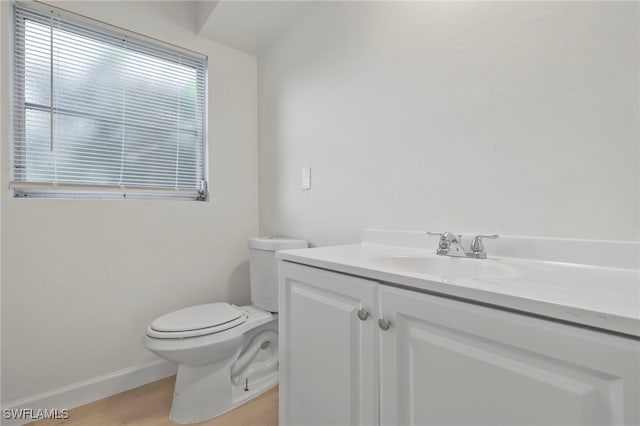 bathroom with toilet, hardwood / wood-style flooring, and vanity