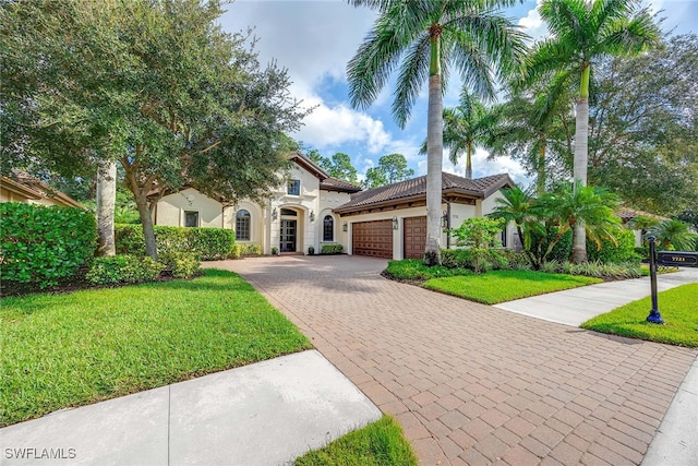 mediterranean / spanish house featuring a front yard and a garage