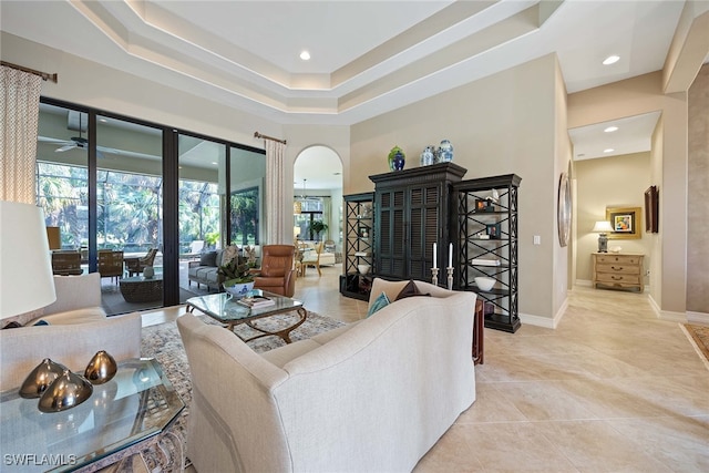 living room featuring light tile patterned floors, a tray ceiling, and ceiling fan