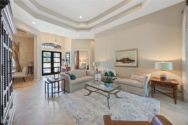 living room with a towering ceiling, light tile patterned floors, a raised ceiling, and french doors