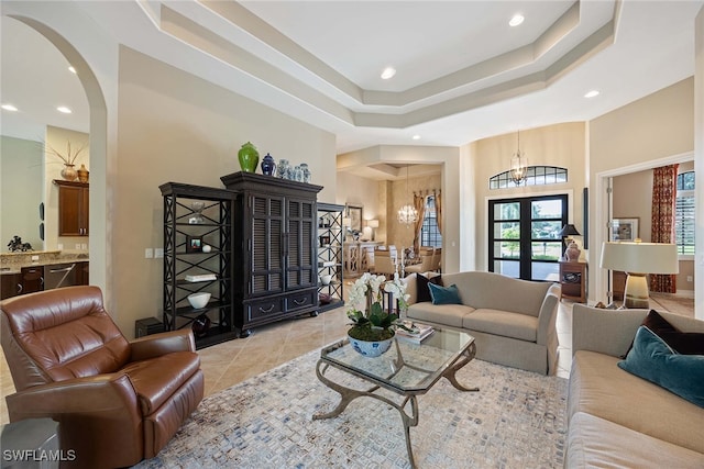 tiled living room with an inviting chandelier and a raised ceiling