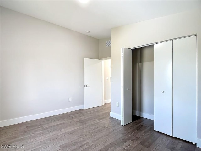 unfurnished bedroom with visible vents, baseboards, a closet, and wood finished floors