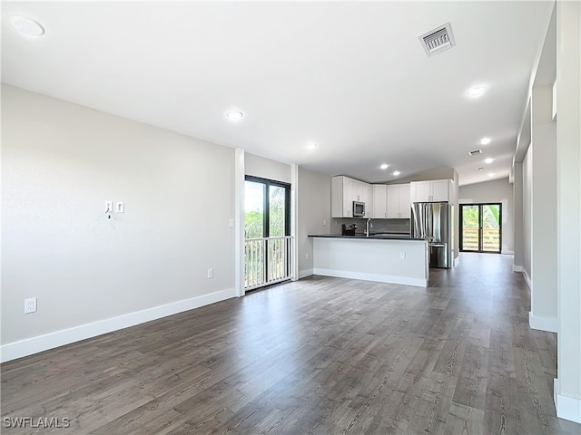 unfurnished living room with dark wood-type flooring, plenty of natural light, and sink