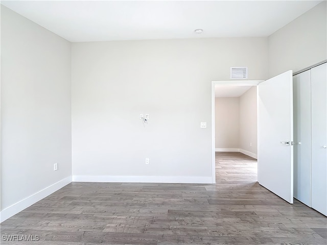 empty room with wood finished floors, visible vents, and baseboards