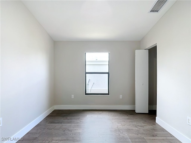 unfurnished room with visible vents, baseboards, and wood finished floors