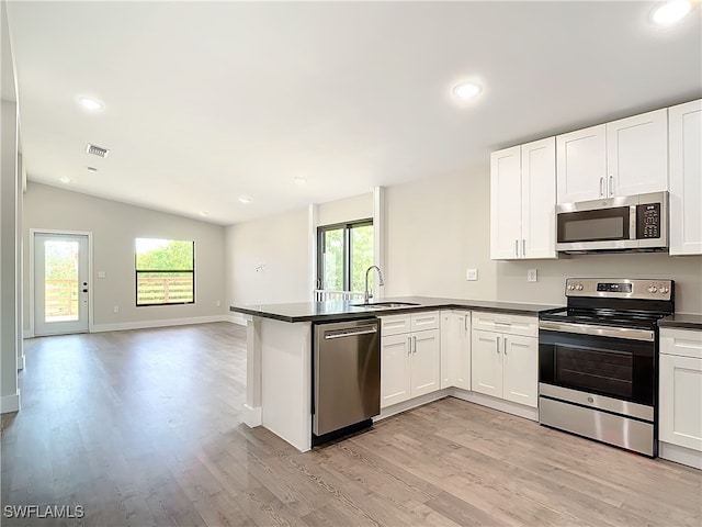 kitchen with dark countertops, visible vents, appliances with stainless steel finishes, a peninsula, and a sink