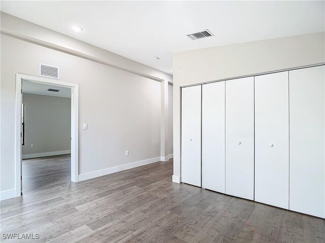 unfurnished bedroom featuring vaulted ceiling, hardwood / wood-style floors, and a closet