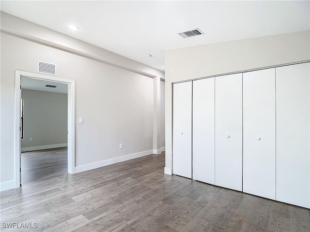 unfurnished bedroom featuring light wood-style floors, visible vents, a closet, and baseboards