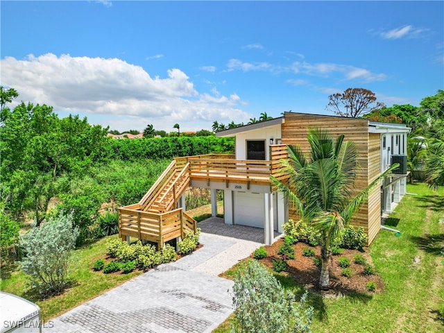 view of front of home with an attached garage, a front lawn, stairs, stucco siding, and driveway