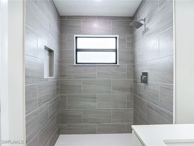 bathroom with tiled shower and vanity