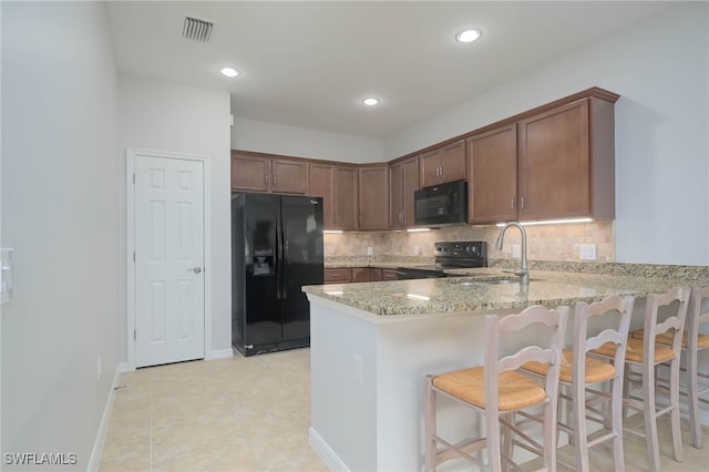 kitchen featuring backsplash, black appliances, kitchen peninsula, sink, and light stone countertops