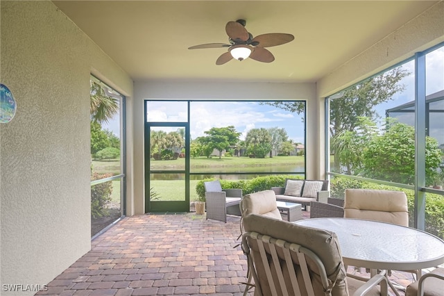 sunroom / solarium with a wealth of natural light, ceiling fan, and a water view