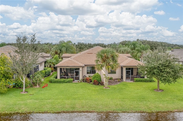 view of front of home with a sunroom, a front yard, and a water view