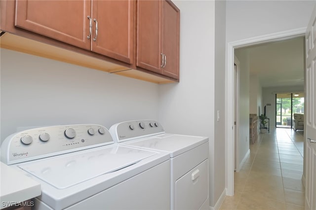 laundry area with cabinets, light tile patterned floors, and independent washer and dryer