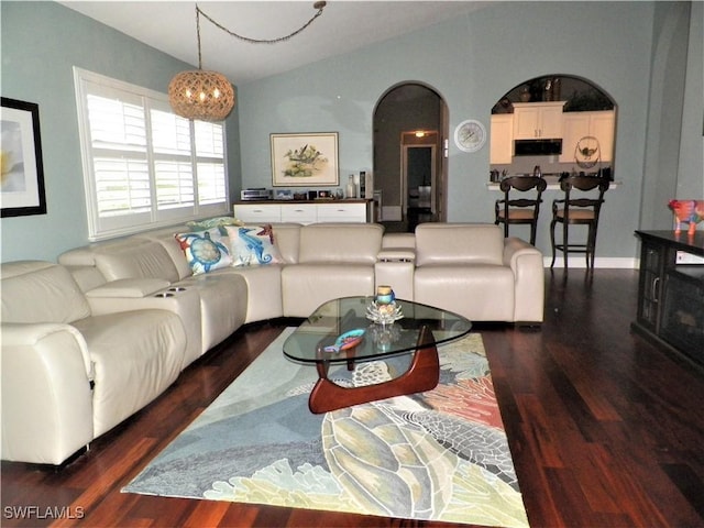 living room featuring lofted ceiling, arched walkways, wood finished floors, and an inviting chandelier