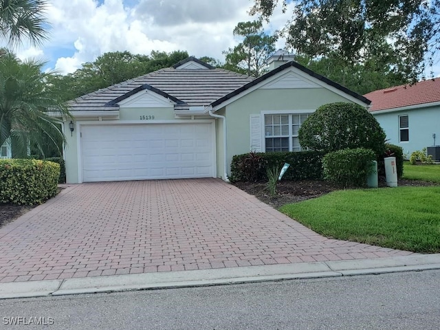 ranch-style home featuring cooling unit, a garage, and a front yard