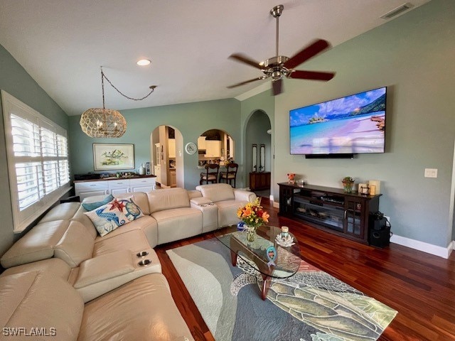 living room featuring ceiling fan with notable chandelier, dark wood-type flooring, and lofted ceiling