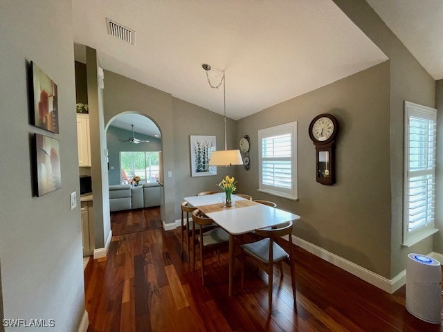 dining area with dark wood-type flooring and vaulted ceiling