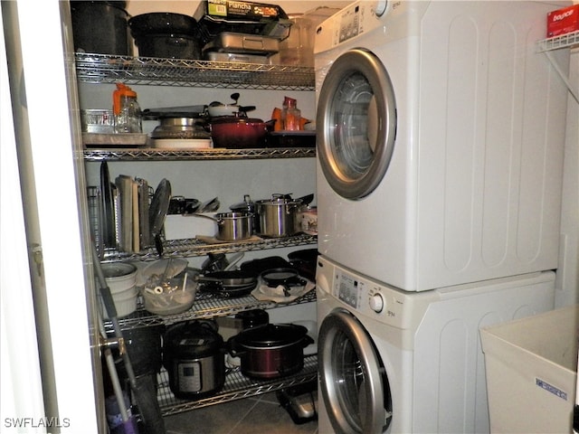 washroom with tile patterned floors, stacked washer and dryer, and sink