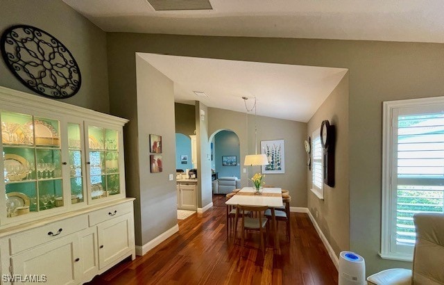 dining space featuring dark wood-type flooring, lofted ceiling, and a healthy amount of sunlight