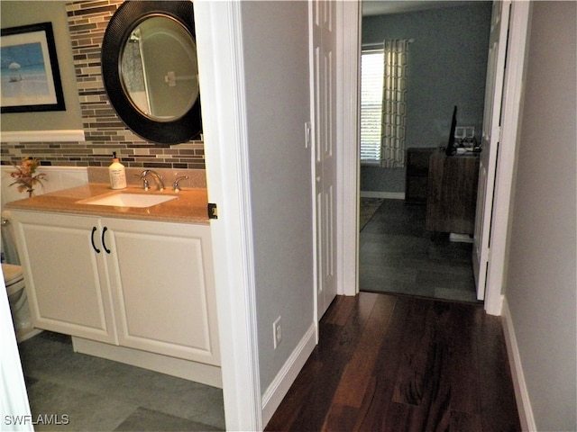 bathroom with hardwood / wood-style floors, toilet, tasteful backsplash, and vanity