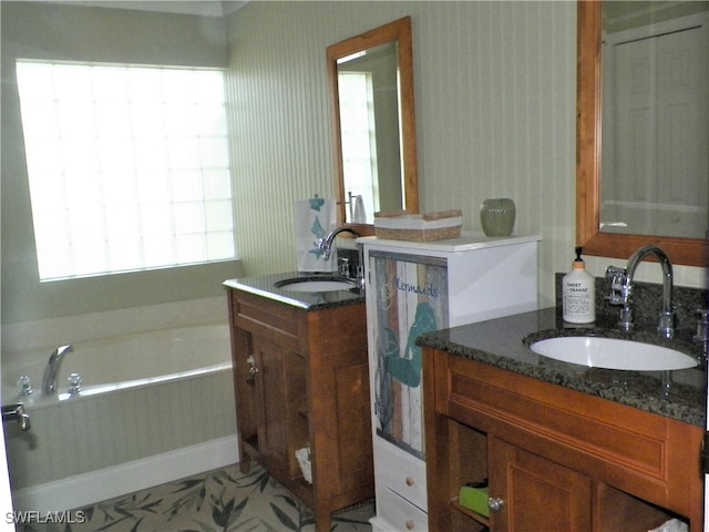 bathroom with a tub to relax in, vanity, and tile patterned floors