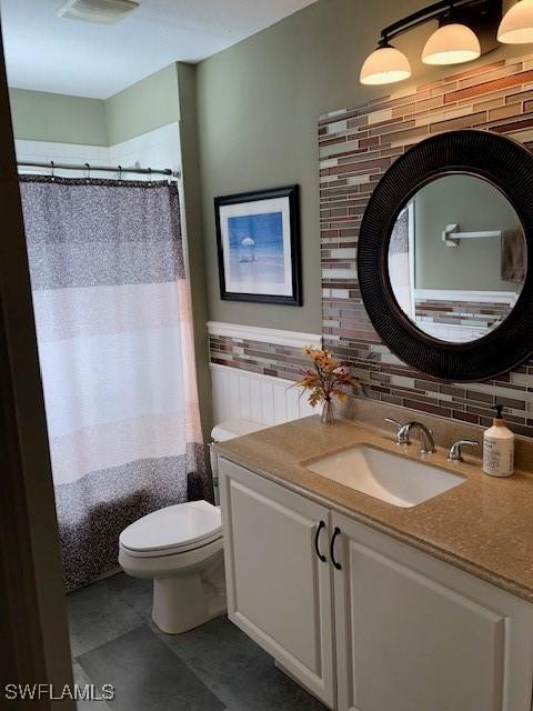 bathroom featuring vanity, tile walls, and toilet